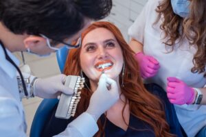 Dentist installing porcelain veneers on female client